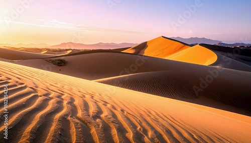 Fototapeta Naklejka Na Ścianę i Meble -  Vast desert landscape with undulating sand dunes bathed in the warm glow of sunset, highlighting the intricate patterns of wind-blown sand.