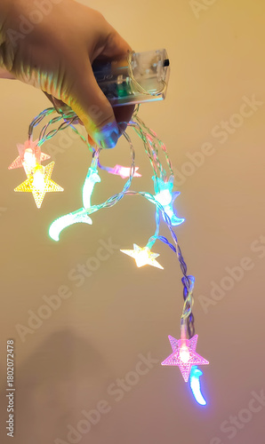 Hanging holiday garlands shimmer gently in warm tones. The moment reflects coziness, joy, and seasonal warmth.