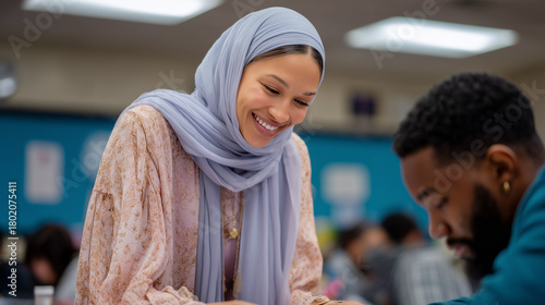 Muslim woman smiling while teaching in classroom with students around  