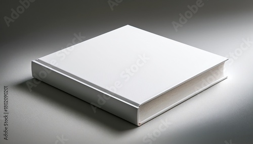 a thick square blank white book rests on a light gray surface casting a subtle shadow its cover is smooth and unblemished