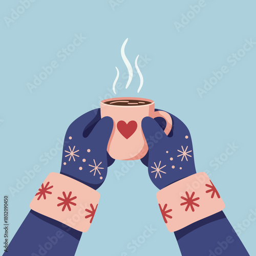 Warm hands holding a cup of hot beverage in winter with heart design on mug 