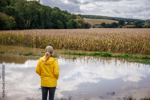 Flood on farm. Worried farmer looking at flooded corn field after rain. Impact of extreme weather and natural disaster due to climate change on agriculture
