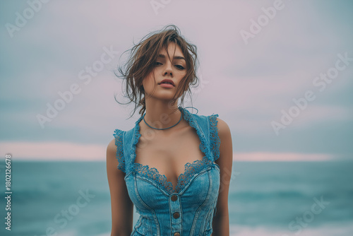 Fashionable woman posing near ocean water in stylish blue outfit serene atmosphere