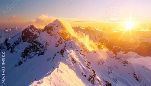 A breathtaking aerial view of snow-covered mountain ranges illuminated by a brilliant sunrise, creating a dramatic and serene landscape.