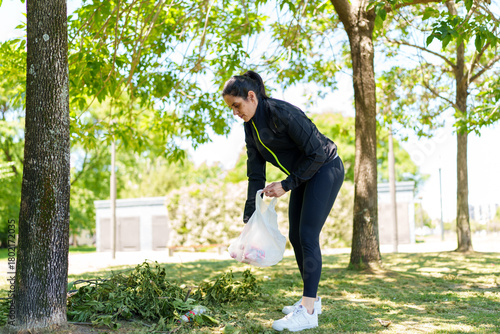 Canvas Print Woman picking up trash in park for environmental cleanup