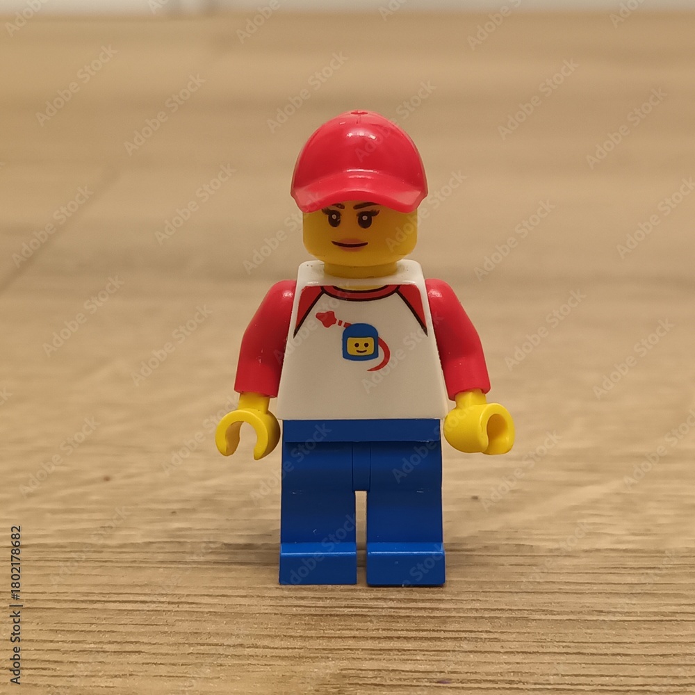 Naklejka premium Lego Minifigure - A Red Hat-Wearing Figure in a White Shirt and Blue Pants