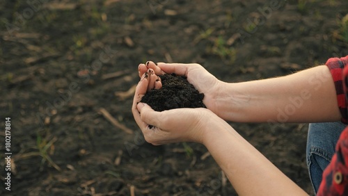 The hands of a peasant woman hold a handful of fertile soil with their bare hands, a view from above. The concept of agriculture, agribusiness.