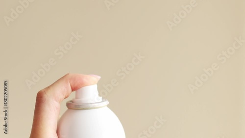 Finger presses spray nozzle releasing fine mist. Concept of deodorant perfume, disinfectant, thermal water or pepper spray — freshness, hygiene, and protection.