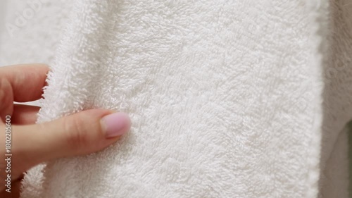 Hand touching soft white bath towel surface. Concept of fabric softness, laundry care, fabric softener and bleach for clean and fresh linens