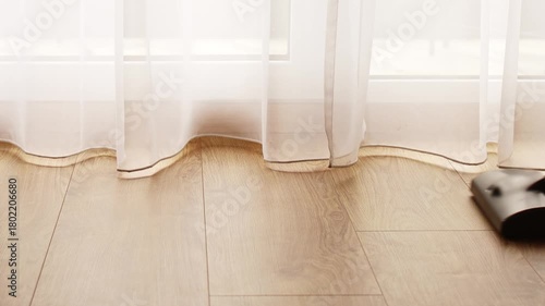 Transparent white curtain tulle moves from the wind from an open window with shadows. Sunny day, the sun's rays sunlight penetrate the room.