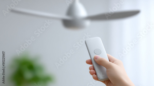 Person holding remote control turning on modern ceiling fan in bright room with natural light
