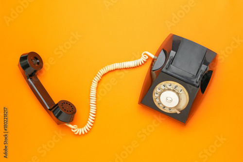 Retro Black Rotary Dial Telephone on Vibrant Orange Background