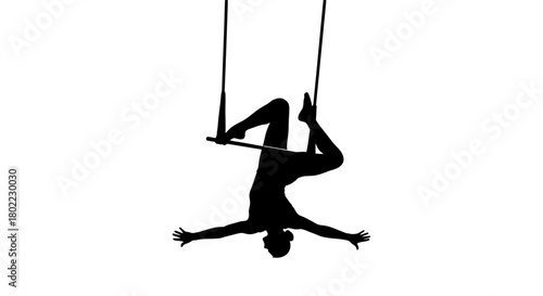 Silhouette of a trapeze artist performing an acrobatic pose, hanging upside down with arms outstretched.