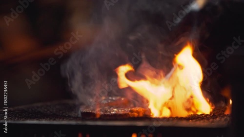Slow motion showing closeup of a torch flame heating a grill plate at a night yatai food stall in Fukuoka, Japan, with sparks, smoke, and glowing light effects