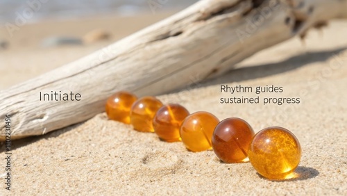 Five Perfectly Smooth Polished Amber Beads Arranged on Sandy Beach Beside Driftwood
