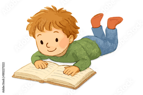 Happy young boy lying on stomach reading an open book