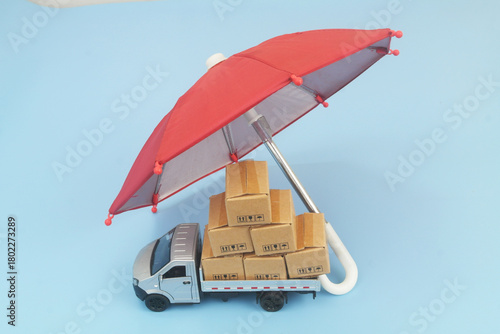 Lorry truck with many boxes under red umbrella on blue background. Protection and insurance for freight transportation concept	