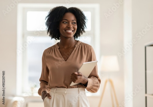 Smiling black woman holding a tablet in a bright room