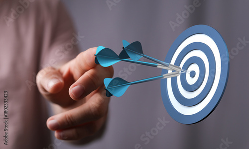Hand throwing darts at a ta...