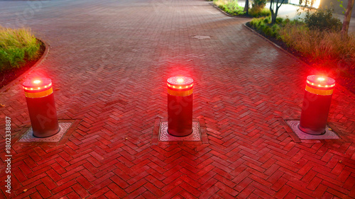 Automatic security hydraulic bollards in night. Lifting metallic bollards to enable or block traffic to protect property.