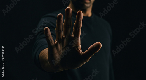 Urgent stop gesture from a man in dark clothing, conveying a powerful message of denial or boundary setting.
