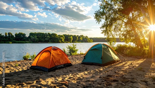 Two camping tents on sandy shore with river and trees, golden sunlight peeking through