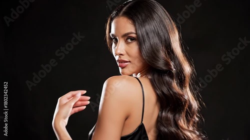 Wallpaper Mural Glamorous Woman with Wavy Hair - This video features a beautiful woman with long, wavy brown hair posing elegantly against a dark background. Torontodigital.ca
