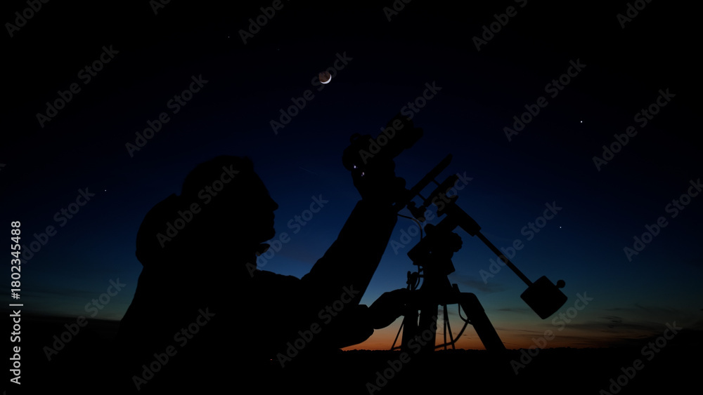 Fototapeta premium Amateur astro-photographer with a camera on a tripod photographing night sky with stars, planets, Moon and other celestial objects.