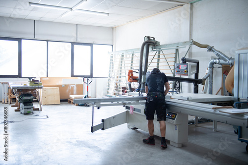 Moderne Werkstatt mit Holzbearbeitungsmaschinen und Handwerker bei der Arbeit