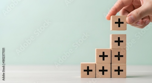 Hand stacking wooden blocks with plus signs to create a growth chart