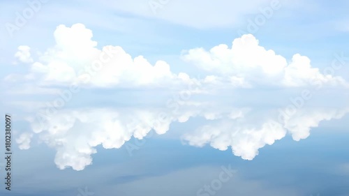 Expansive horizon of a tranquil sky filled with soft, white clouds perfectly mirrored on a still, reflective water surface, evoking peace and serenity