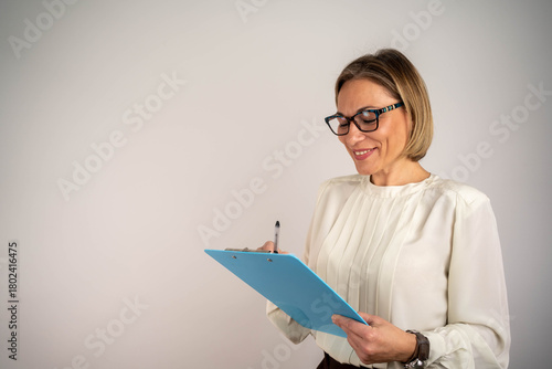 Photo of gorgeous blond secretary woman writing down notes in clipboard