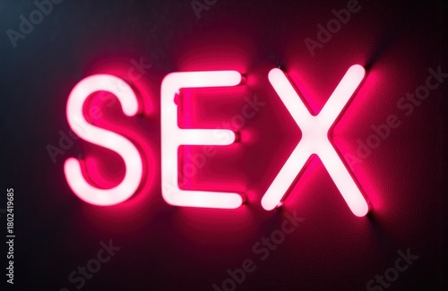 Neon sign spelling SEX glowing in pink against dark background