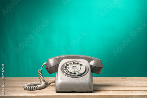 Vintage old telephone on wood table with turquoise wall background