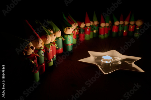 Wichtelfiguren aus Papier als Adventskalender vor einem Sternenteller mit vier Kerzen