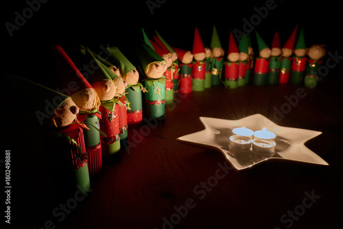 Wichtelfiguren aus Papier als Adventskalender vor einem Sternenteller mit vier Kerzen