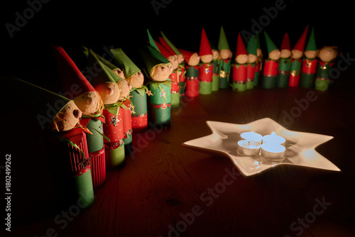 Wichtelfiguren aus Papier als Adventskalender vor einem Sternenteller mit vier Kerzen