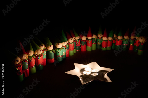 Wichtelfiguren aus Papier als Adventskalender vor einem Sternenteller mit vier Kerzen