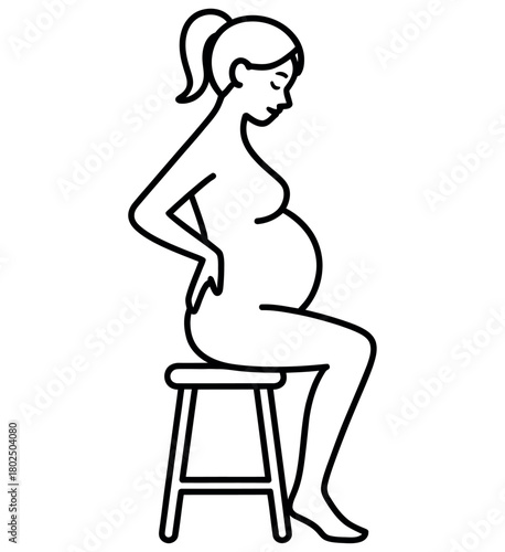 Pregnant woman sits on a stool, cradling her belly with a thoughtful expression.