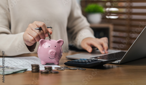 Woman calculate taxes, including dropping coins into Piggy bank, saving money, planning, investing, budgeting, saving cash and financial growth for the future.