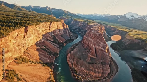 An aerial perspective of a majestic canyon, showcasing the raw beauty and grandeur of nature, with a winding river carving its path through rugged terrain and mountain.