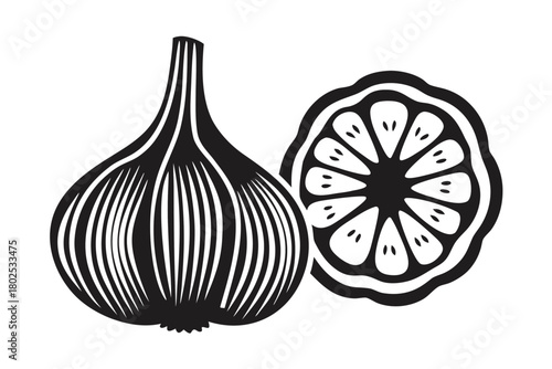 Black and white garlic bulb sits beside a sliced lemon with visible seeds