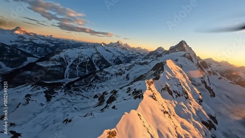 A majestic panorama of snow-capped peaks kissed by the warm glow of the setting sun, offering a breathtaking perspective.