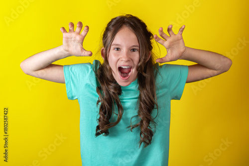 Fotografia Angry young caucasian teen girl holding hands up against yellow background