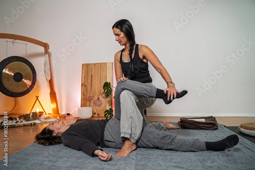 Thai yoga massage, woman masseuse  performing stretches that helps muscles loosen up 