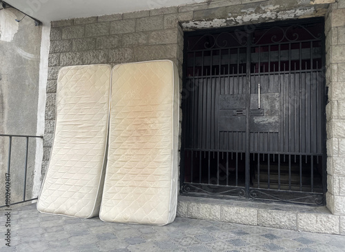 Abandoned Mattresses Leaning Against Building Wall on Urban Street