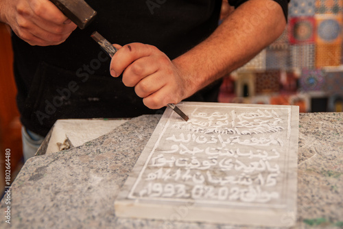 An artisan close up chiseling a stone tablet in the street markets of Fes, Morocco