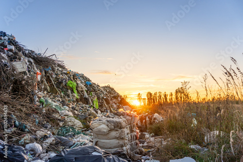 Bilde på lerret Waste management site at sunset with overflowing garbage and natural landscape s