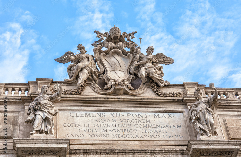 Obraz premium Rome, Italy, Trevi Fountain. Architectural detail of a historic building featuring ornate sculptures and inscriptions under a bright blue sky, showcasing classic design elements and craftsmanship