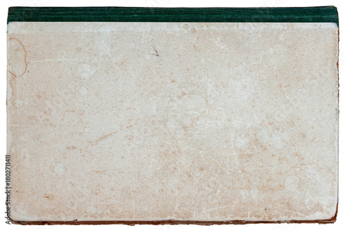 Old worn book cover with a stained beige surface and a dark green spine shows age and texture. Concept of vintage book age, retro book wear, retro book texture. Copy space